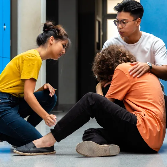 Teenagers in school hallway tending to friend having a medical crisis