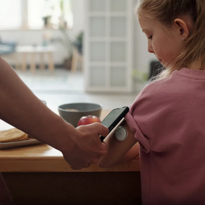 Girl with continuous glucose monitor and phone for monitoring.
