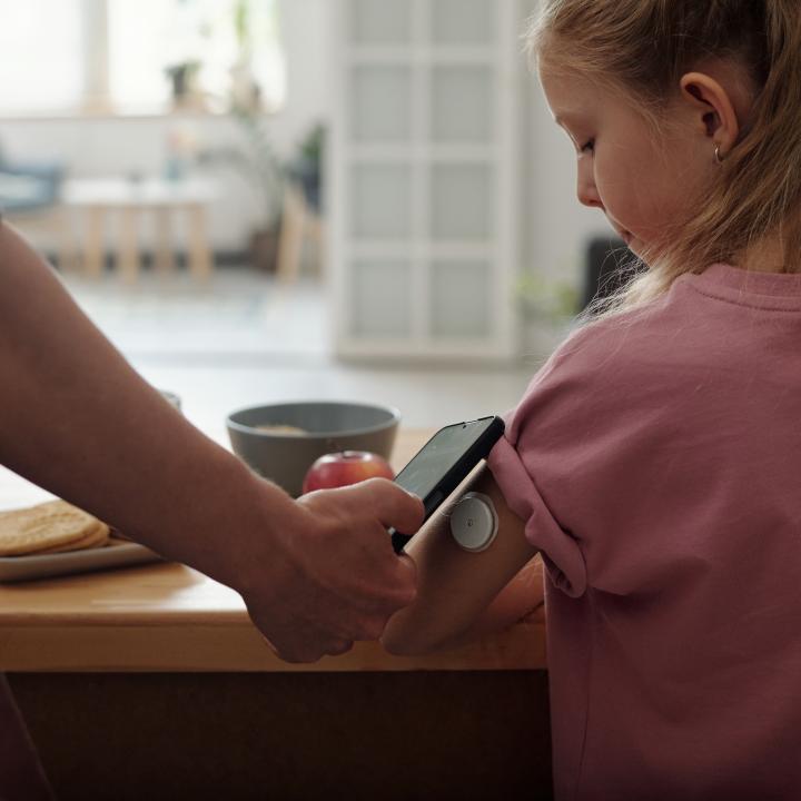 Girl with continuous glucose monitor and phone for monitoring.

