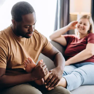 African American man applying diabetic foot cream to woman's foot