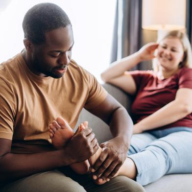 African American man applying diabetic foot cream to woman's foot