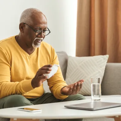 mature black man taking medication pill at home