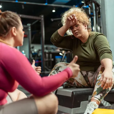 Two women sitting down at the gym after working out