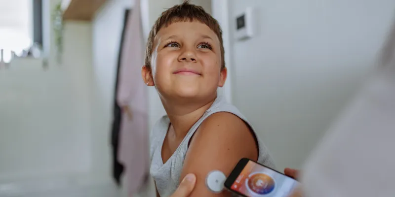 Boy with cgm on arm having his blood glucose level checked
