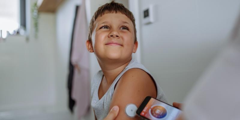 Boy with cgm on arm having his blood glucose level checked