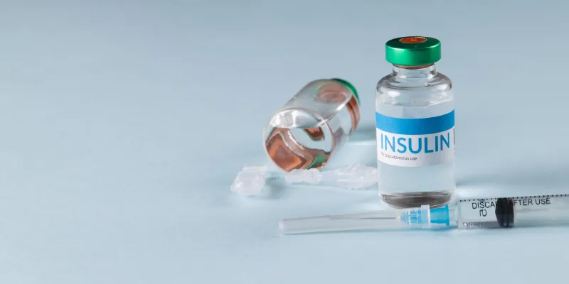 insulin vial and syringe on a light blue background