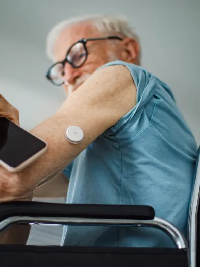 Senior man in wheelchair using smartphone to check his CGM