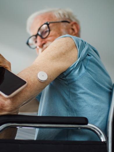 Senior man in wheelchair using smartphone to check his CGM