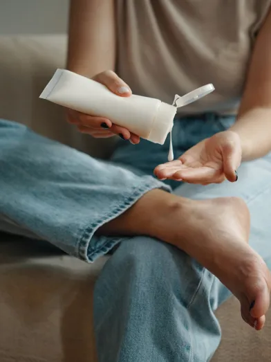Woman putting diabetic foot cream on her hand before applying on her foot