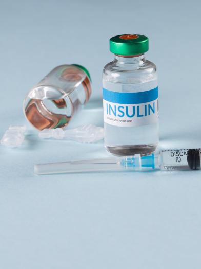 insulin vial and syringe on a light blue background